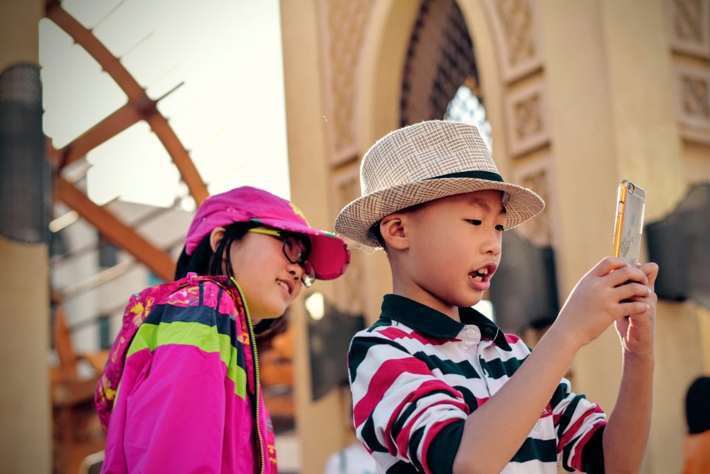 A photo of two children taking selfies on a smartphone
